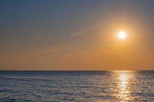 wazig van tropische kleurrijke zonsondergang over de oceaan op het strand. op thailand toerisme achtergrond met zee strand. vakantie reis bestemming foto