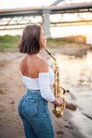 vrouw die saxofoon speelt bij zonsondergang foto