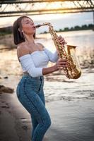 vrouw die saxofoon speelt bij zonsondergang foto