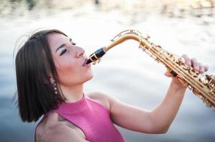 vrouw saxofoon spelen bij zonsondergang. foto