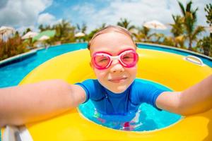 portret van schattig meisje met opblaasbare rubberen ring die plezier heeft in het zwembad foto