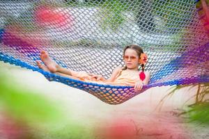 schattig klein meisje op zomervakantie ontspannen in een hangmat foto