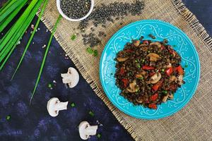 heerlijke linzen met peper en champignons op donkere achtergrond foto