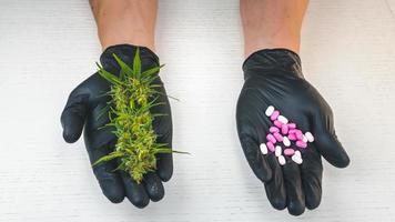 de persoon houdt medische marihuanaknoppen en pillen in zijn hand. foto