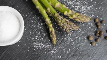 close-up van biologische verse groene asperges met zout en peper. concept van gezond vegetarisch eten, dieet en thuis koken. foto