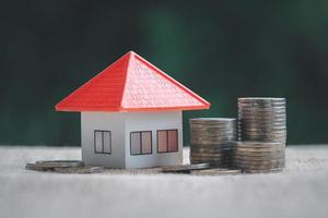 stapel munten met oranje kleur model huis op tafel, financiële strategie idee. investeringen in onroerend goed. hypotheken. leasen. geld sparen voor toekomst en pensioen. foto