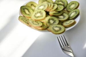 Kiwi fruitplakken op een witte plaat met een vork foto