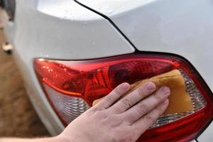 een witte auto met de hand wassen met een spons foto