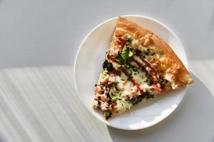 driehoekige plak pizza op een witte plaat foto