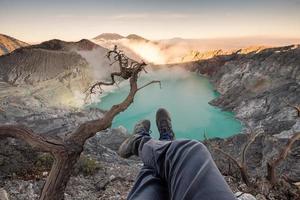 toeristische hangende benen op krater kawah ijen met smaragdgroen meer bij zonsopgang foto