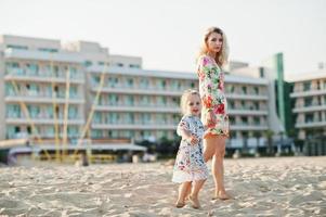 moeder en mooie dochter hebben plezier op het strand. portret van gelukkige vrouw met schattig klein meisje op vakantie. foto
