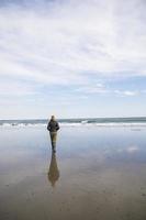 vrouw die in de winter op het strand loopt foto