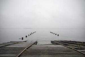 oude pier verzonken in de oceaan op een mistige dag foto