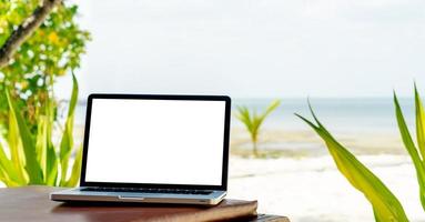 laptop met leeg scherm op strandstoel dichtbij het strand, reiswerkconcept foto