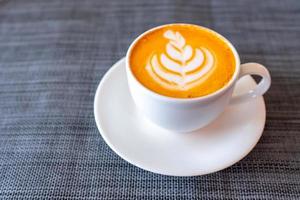 hete thee met latte art in witte koffiekop foto