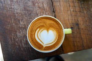 bovenaanzicht van latte koffie of cappuccino koffie in witte kop met mooie boom latte art op houten tafel. foto