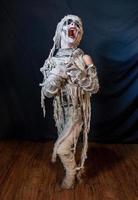 studio-opname portret van jonge jongen in kostuum gekleed als een halloween, cosplay van enge mummie pose op geïsoleerde zwarte achtergrond foto