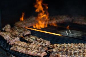 gegrilde worst met toevoeging van kruiden en groenten op de grillplaat, buitenshuis. grillen van voedsel, bbq, barbecue foto