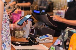 vrouw die rekening betaalt via smartphone met behulp van nfc-technologie in een restaurant. foto