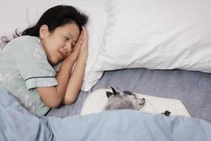 gelukkig lachende vrouw slapen met een hond in bed thuis. foto