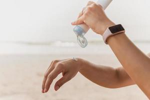 vrouw knijpt zonnebrandcrème uit een buis op de zee strand uv-bescherming. foto