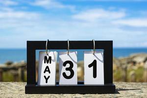 31 mei kalenderdatumtekst op houten frame met onscherpe achtergrond van oceaan foto