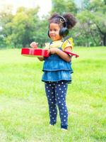 het meisje staat op het gras, draagt een koptelefoon en leert ukelele-snaren spelen foto