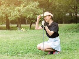 een jonge Aziatische golfer kijkt naar de lijn op de golfbaan en bereidt zich voor om de bal te leggen tijdens de wedstrijd foto