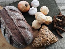 brood, uien, knoflook en crackers op een bruine achtergrond foto