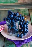 takje blauwe druiven in een glas op een plaat, verticaal