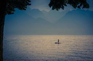 man op een surfplank met peddel op het meer van leman, zwitserland foto