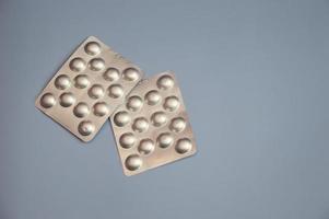tabletten in een zilveren blister op een blauwe achtergrond. vrije ruimte voor tekst. farmaceutica, medicijnen, vitamines, bioadditieven. gezondheidszorg. foto