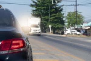 achterkant van sedarn auto zwarte kleur op de asfaltweg. met verkeersomstandigheden en hete zon gedurende de dag en andere auto's die tegenover de lens rijden. foto