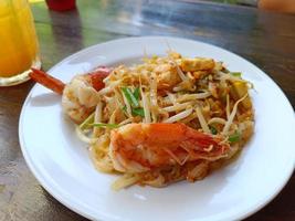 pad thai met verse garnalen op een witte plaat op de bruine tafel populair thais eten foto