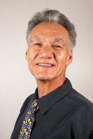 volwassen man van 60 plus met een zwart shirt en een kleurrijke stropdas tegen een witte achtergrond foto