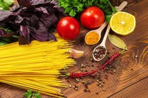 rauwe pasta, groenten, basilicum en specerijen op de houten tafel