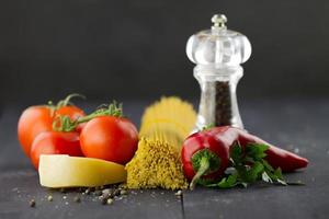 Italiaanse ingrediënten: spaghetti, kruiden, tomaten, Spaanse peper op houten achtergrond foto