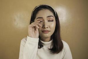 tranen vergieten en droevige uitdrukking van jonge Aziatische vrouw in wit overhemd foto
