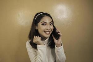 glimlachende jonge aziatische vrouw met een handgebaar voor praten of bellen? foto