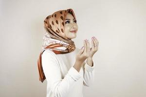 gelukkig mooi aziatisch moslimmeisje dat een hoofddoek draagt die tot god bidt. foto