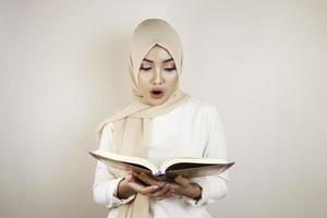 jonge aziatische moslimvrouw die een hoofddoek draagt die de koran leest foto