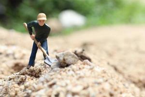 miniatuur werkpop met schop om te werken, mijnwerker man aan het werk klein figuur speelgoedmodel grond graven of tuinieren foto