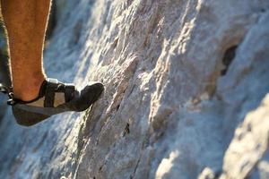 klimschoenen aan de voet van de klimmer rusten de teen op de rots. extreme sporten, bergtoerisme. detailopname. ruimte kopiëren. harige mannelijke been foto