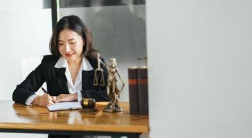 jonge serieuze Aziatische vrouwelijke ceo advocaat zakenvrouw zittend aan een bureau werken typen op laptopcomputer in hedendaags corporatiekantoor. bedrijfstechnologieën concept. foto