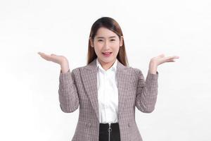 Aziatische werkende vrouw lacht en toont haar handen om iets op de witte achtergrond te presenteren. foto