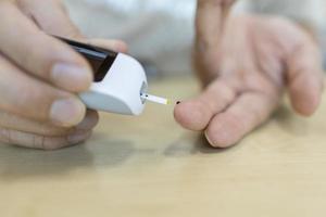 close-up van man handen met behulp van glucosemeter op vinger om de bloedsuikerspiegel te controleren. gebruik als medicijn, diabetes, glycemie, gezondheidszorg en mensenconcept. foto