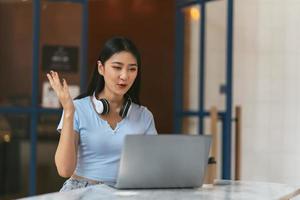 Aziatische vrouw met videogesprek op haar computer thuis. lachend meisje dat online studeert bij de leraar. foto