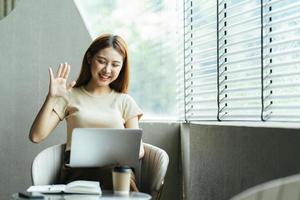 Aziatische vrouw met videogesprek op haar computer thuis. lachend meisje dat online studeert bij de leraar. foto