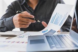 strategie analyse concept, zakenman werken financieel manager onderzoeken proces boekhouding berekenen analyseren markt grafiek data voorraad informatie review op tafel in kantoor. foto