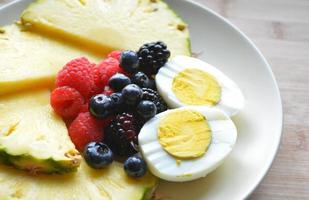 gezond ontbijtbord met ananas, bosbessen, frambozen en gekookte eieren